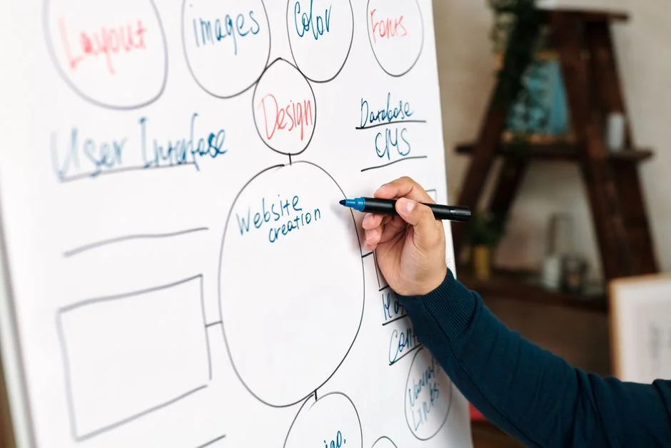 Close-up view of vibrant design sketches in a spiral notebook, alongside color swatches on a white desk.